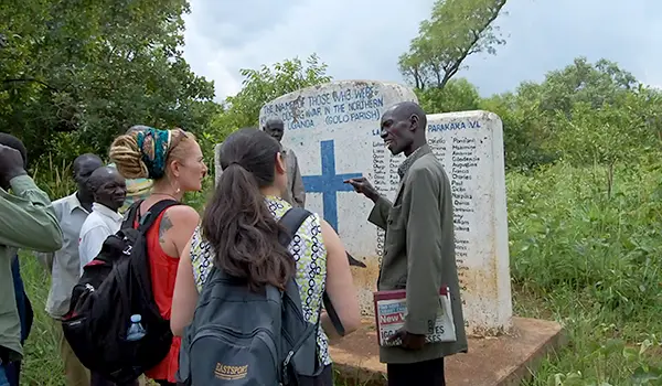 A man points to a sign with a group with backpacks on listen